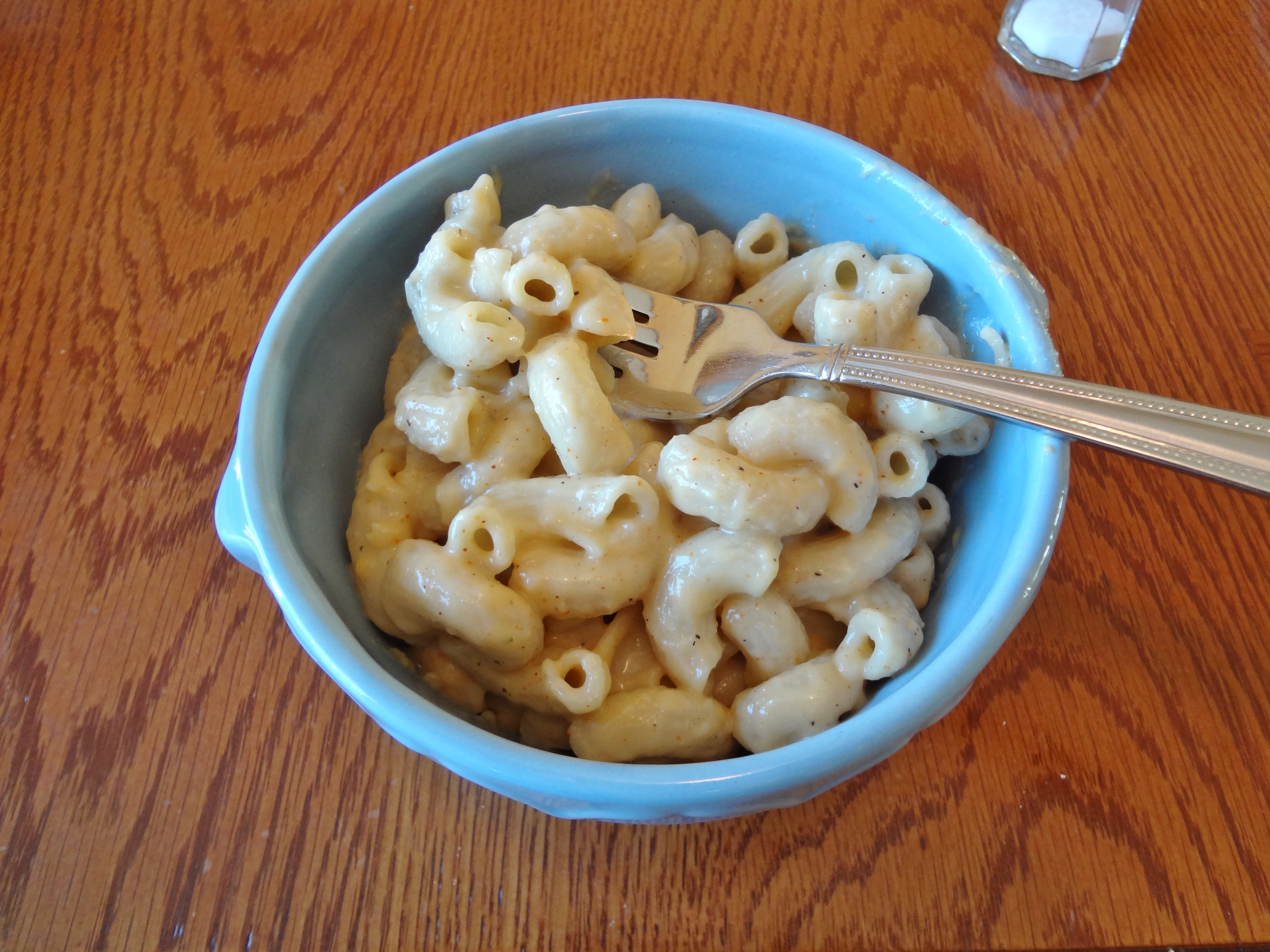 vegan mac and cheese in a blue bowl with a fork. 